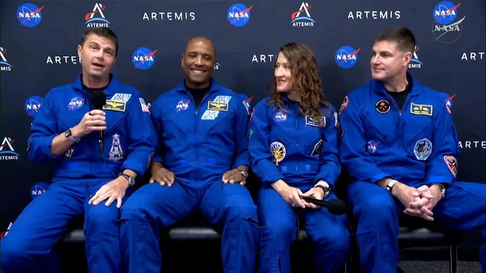 Οι αστροναύτες της Artemis II Wiseman, Glover, Koch και Hansen με μπλε στολές πτήσης μπροστά σε φόντο της NASA